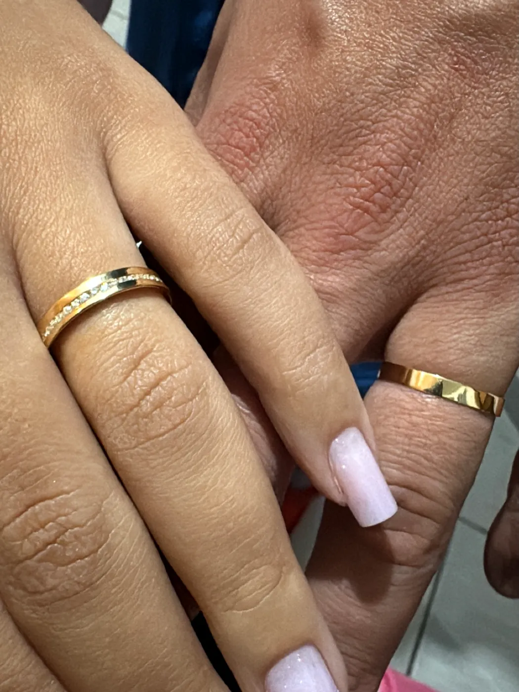 Par de alianças de ouro nas mãos do casal